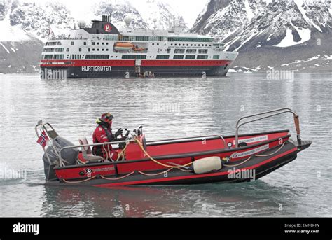 Zodiac boat with Hurtigruten's arctic cruise ship MV Fram, moored in Magdalenefjorden, north ...