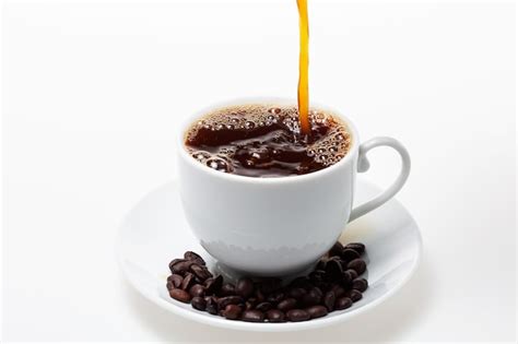 Premium Photo | Pouring coffee into white coffee cup and beans on white background