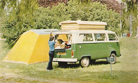 a woman standing next to a green van with a yellow tent on the back ground