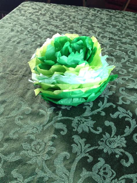 a green and white flower sitting on top of a table covered in paper machs