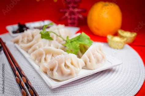 "Chinese Jiaozi new year food with sauce and white placemat on red background. People will eat ...