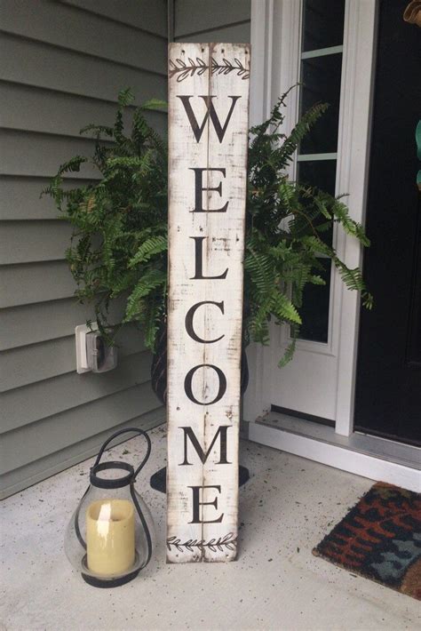 a welcome sign sitting on the front porch next to a potted plant and candle