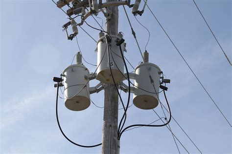 Three Phase Transformers on pole with light blue sky - Metglas, Inc.