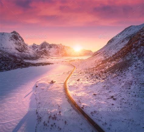 Beautiful road in snowy mountains in winter at sunset Stock Photo by den-belitsky