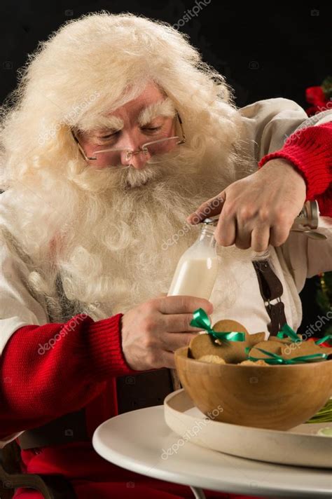 Santa Claus eating cookies with milk — Stock Photo © HASLOO #36520183