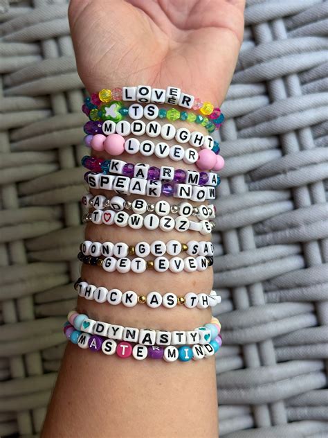 several bracelets with words written on them in different colors and sizes are held up by a ...