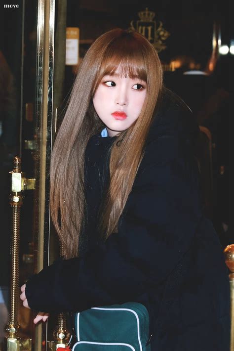 a woman with long hair sitting in front of a glass door wearing a black coat