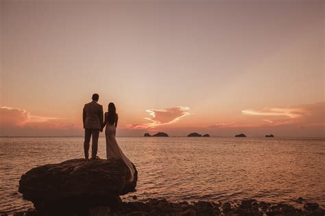 Couple on rock looking out at sunset sea - photo by Ed Peers Photography