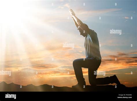 Side View Of A Man Kneeling And Praying Against Cloudy Sky At Sunset Stock Photo - Alamy