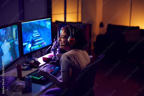 Teenage Girl Wearing Headset Gaming At Home Using Dual Computer Screens ...