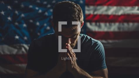 A man prays for america in front of a flag — Photo — Lightstock