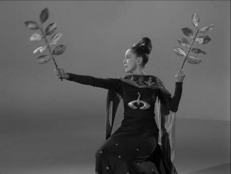 a woman sitting on top of a chair holding two flowers in one hand and an umbrella in the other