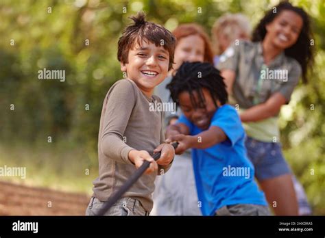 Learning teamwork through play. A group of kids in a tug-of-war game Stock Photo - Alamy