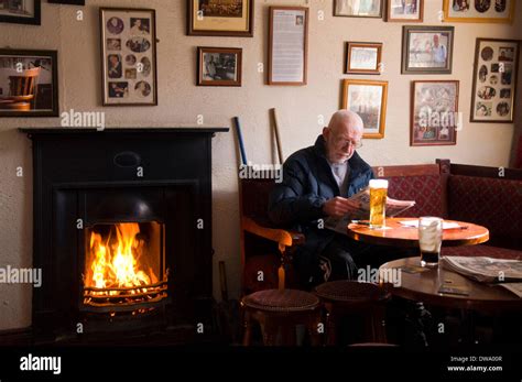 A man enjoys a pint by the fire in Corner House Bar in Ardara, County Donegal, Ireland Stock ...