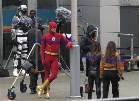 the flash is walking down the street with some people behind him and another man in costume