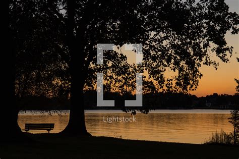 Sunset and a park bench near a lake — Photo — Lightstock