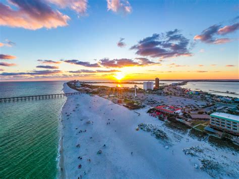 an aerial view of the beach and pier at sunset