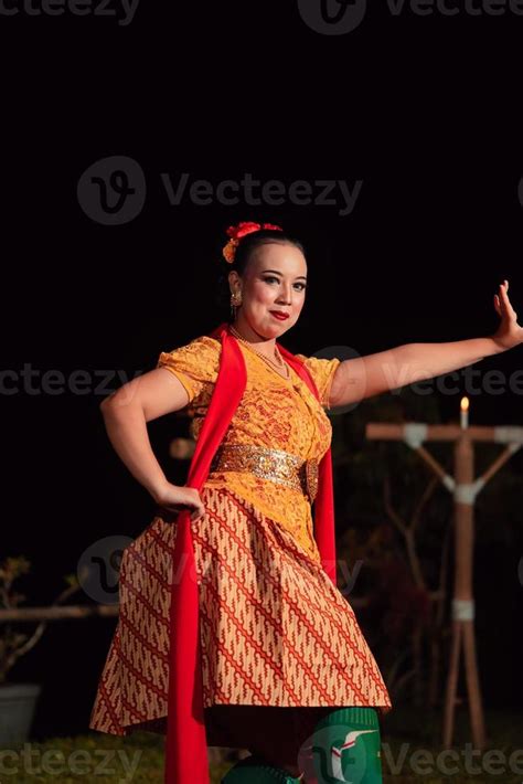 Balinese dancer with an orange costume and wearing makeup posing like a ...