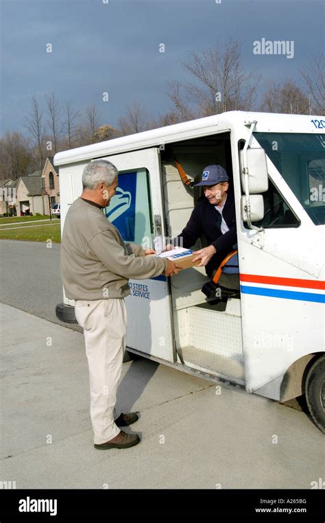 Postal carrier driving a mail truck delivers mail to male home owner ...