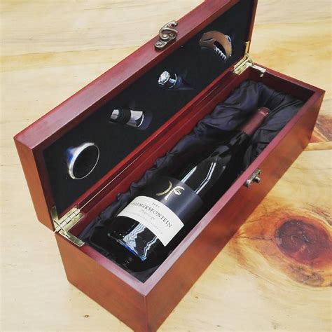 an open wooden box containing two bottles of wine and a corkscrew ...