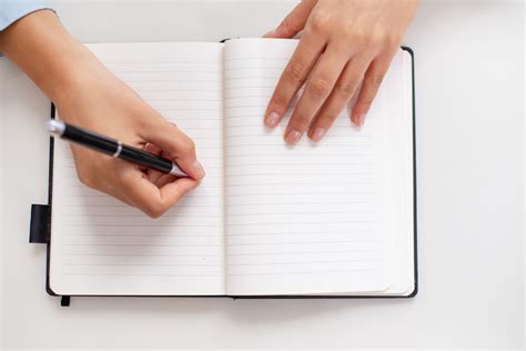 Top view of female hands writing in notebook on desk - Gym Élite Coach