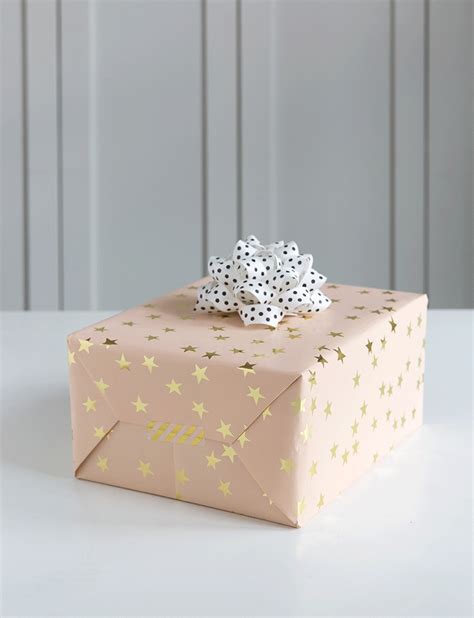 a pink gift box with gold stars and polka dots on it sitting on a white ...