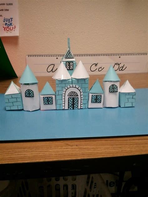 a paper model of a castle on top of a blue table with a ruler in the ...