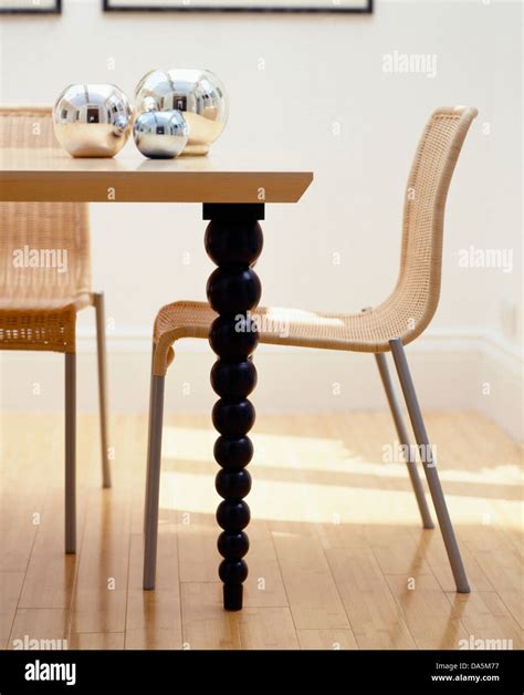 Wicker+metal chairs at wooden table with turned spindle legs in modern dining room Stock Photo ...