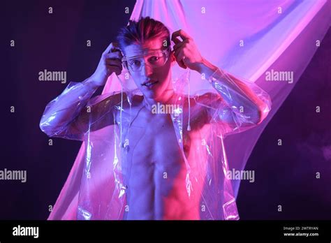 Stylish young man wearing clear coat and glasses in neon lights Stock Photo - Alamy