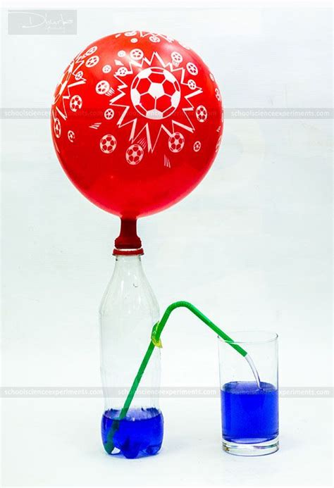 a red ball sitting on top of a glass next to a blue liquid