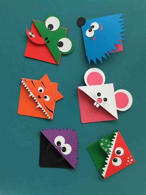 some paper animals that are on top of a blue surface with one animal sticking out of it's mouth