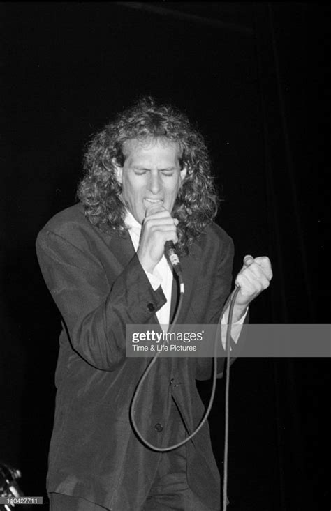 a man with long hair holding a microphone in front of his face while ...