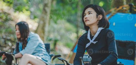 Young women sitting and drink beverage front of camping tent 21043163 Stock Photo at Vecteezy