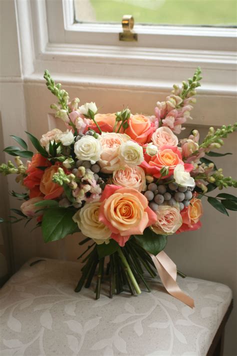 Wedding bouquet in pink and peach with roses, snapdragons, spray roses, tulips, brunia and ...