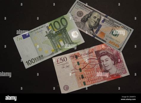 Flat lay view of 100 Euro, 50 GBP, 100 Dollar banknotes on a black ...