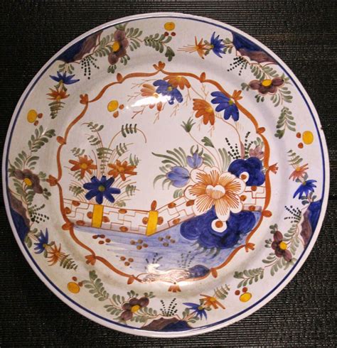 a decorative plate with blue and orange flowers on it's rim is sitting on a black surface