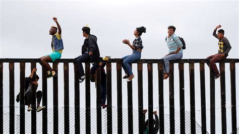 Asylum seekers climb US border wall as migrant caravan gathers on ...