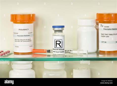 Vial of regular insulin and syringe on medicine cabinet shelf. Labels ...