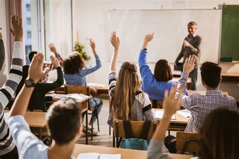 Back view of high school students raising hands on a class.