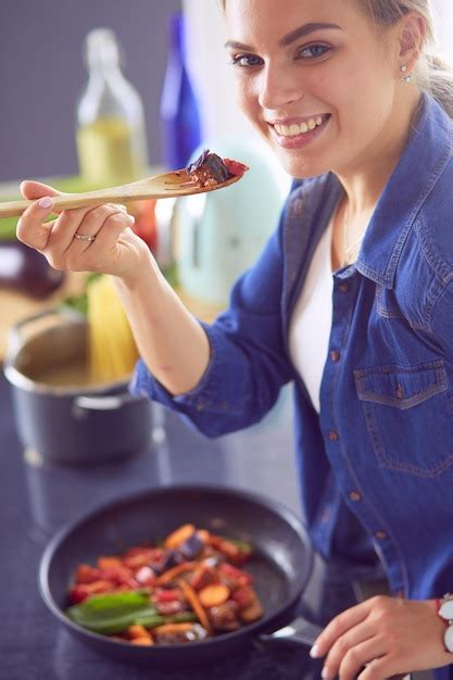 Premium Photo | Young woman cooking healthy food holding a pan with ...