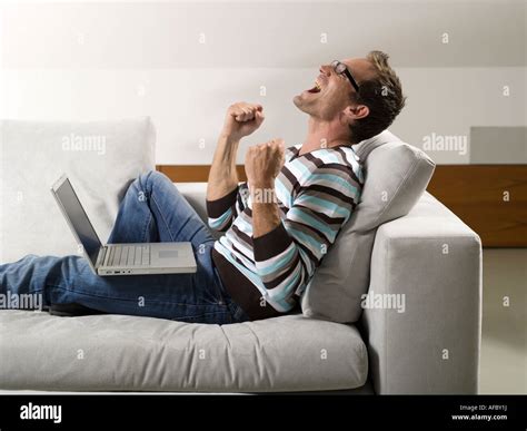 Man sitting on sofa, using laptop Stock Photo - Alamy