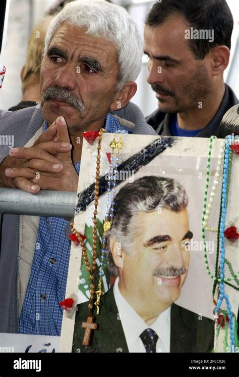 An unidentified man stands behind a portrait of slain former Lebanese ...