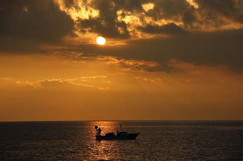 Free picture: Silhouette of fishing boat in distance in orange yellow sunset on lakeside