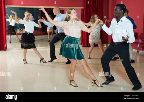 Adult dancing couples enjoying active boogie-woogie in modern studio ...