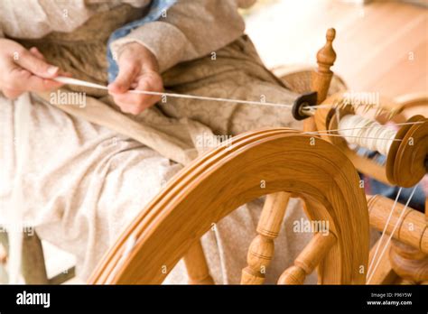 a woman spinning wool into yarn on a spinning wheel Stock Photo - Alamy