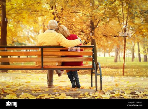 Elderly couple sitting on bench in autumn park Stock Photo - Alamy