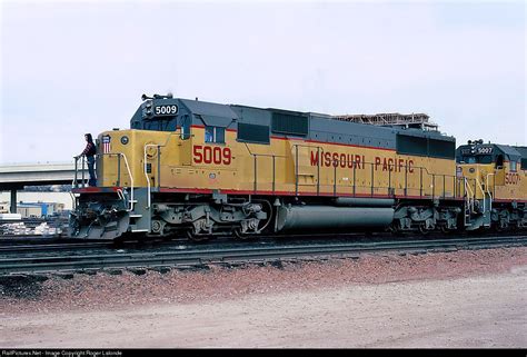 a yellow and black train traveling down tracks