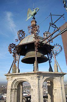 an old bell tower with a bird on it's top and the city in the background