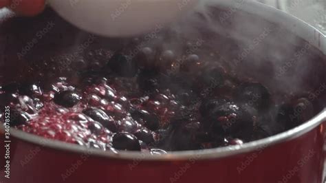 Cooking delicious red fruit jam, mixing and kneading. Close up ...