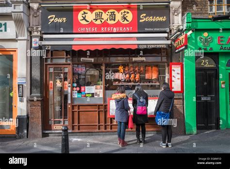 Three young asian women looking at menu outside the Four Seasons chinese restaurant in London's ...